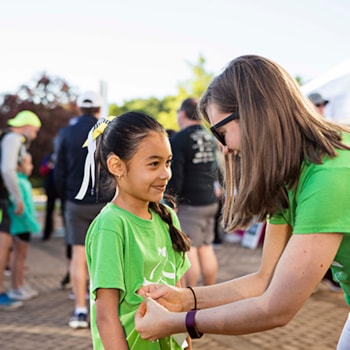 Girls on the Run coach helping to attach running bib on participants shirt